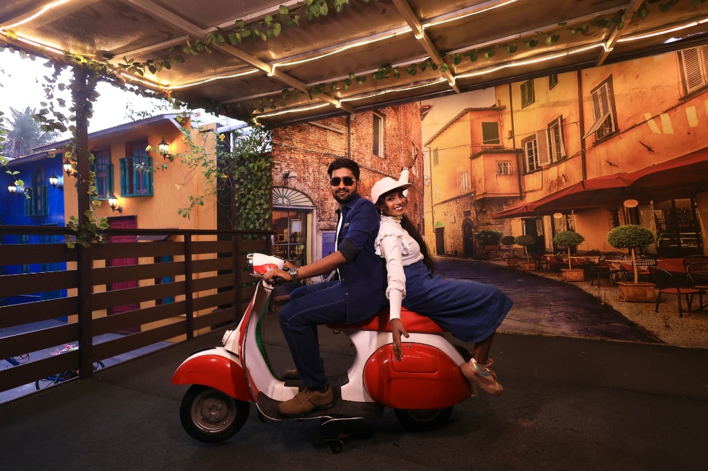 Couple posing on a red scooter at a themed street set